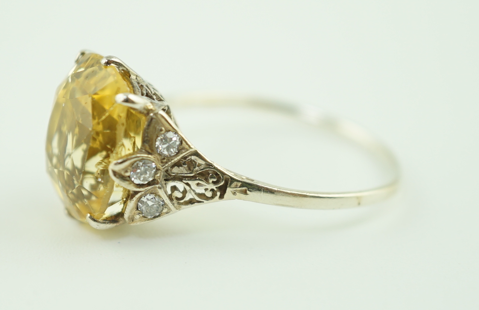 A mid 20th century platinum? and single stone fancy cushion cut yellow sapphire set dress ring with six stone diamond set pierced mount